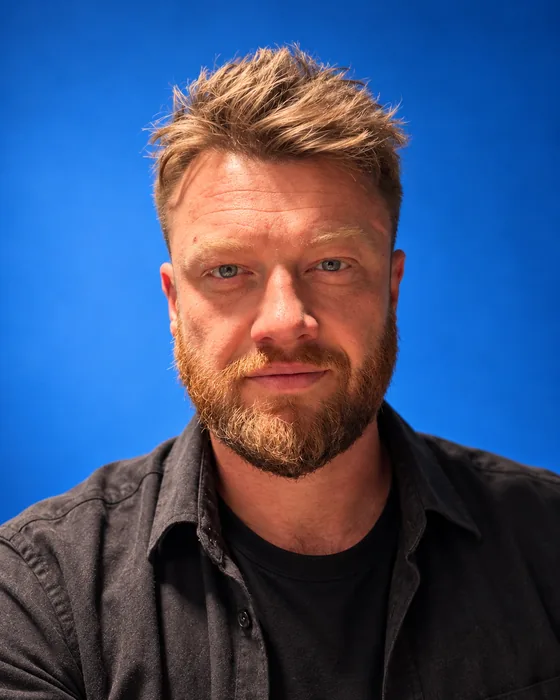 Tim-Ralf Heise, Verleger und Programmleiter des Rauschwerk Verlags, Porträt vor blauem Hintergrund